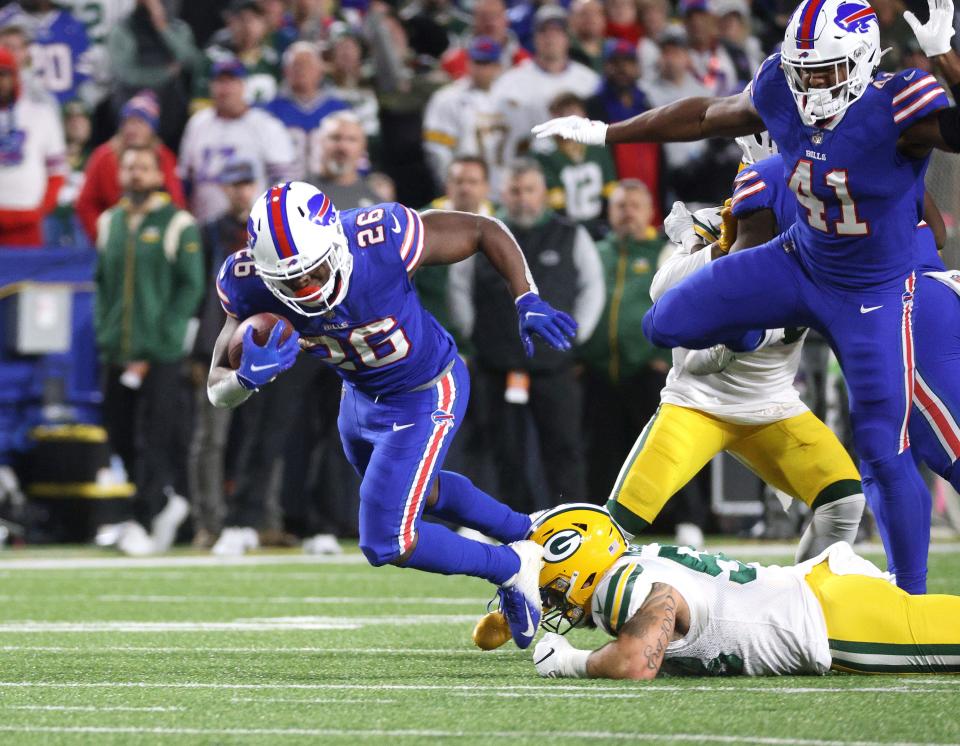 Bills running back Devin Singletary is tripped up by Packers Isaiah McDuffie.
