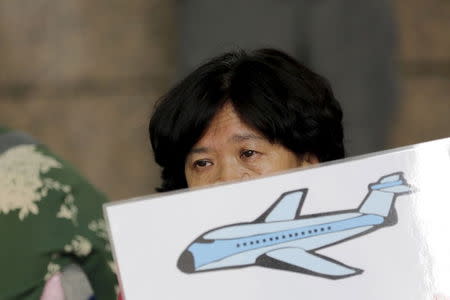 A woman whose relative was aboard Malaysian Airlines flight MH370 holds a placard as she and other family members express their demands to Malaysia Airlines outside its Beijing office August 6, 2015. REUTERS/Jason Lee