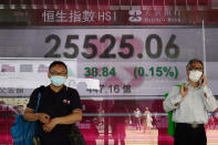 A man walks past a bank electronic board showing the Hong Kong share index outside a Hong Kong local bank Wednesday 26, 2020. Asian shares were mostly lower Wednesday after a lackluster session on Wall Street following talks between the United States and China on the status of a deal meant to work as truce in their trade war. (AP Photo/Vincent Yu)