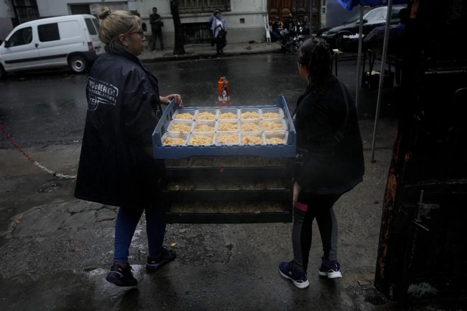 ARCHIVO - Voluntarios cargan una bandeja de comida caliente afuera de un comedor comunitario administrado por el Movimiento de Trabajadores Excluidos (MTE) en Buenos Aires, Argentina, el miércoles 13 de marzo de 2024. (AP Foto/Natacha Pisarenko, Archivo)