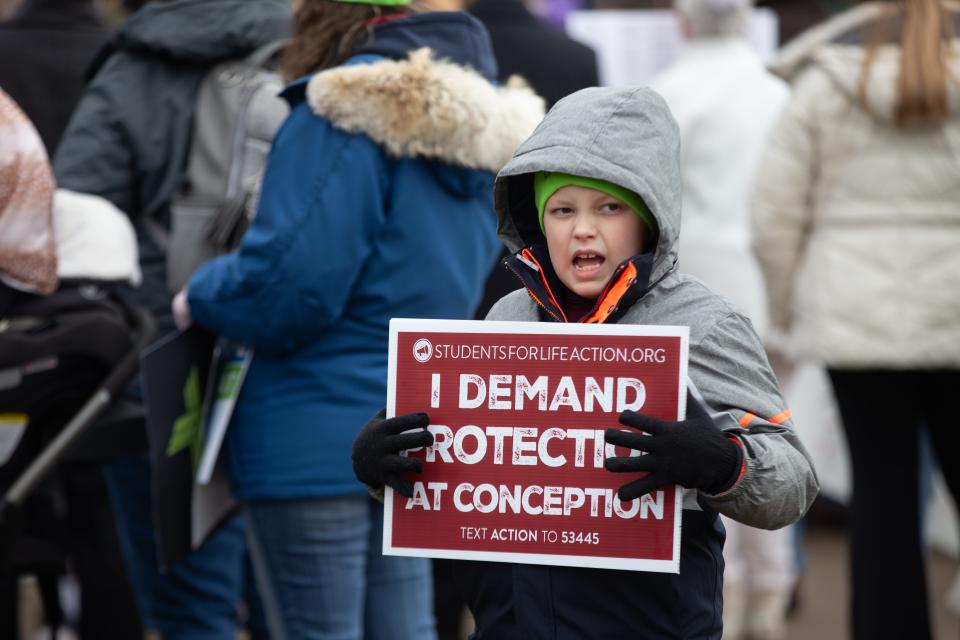 A young anti-abortion supporter holds a sign from Students For Life Action during the March for Life rally in downtown Topeka.