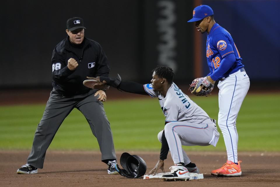 Miami Marlins' Jazz Chisholm Jr., center, gestures for a review after he was called out on a tag at second base as New York Mets' Francisco Lindor, right, and umpire Doug Eddings watch during the eighth inning in the second baseball game of a doubleheader Wednesday, Sept. 27, 2023, in New York. After review, the call on the field was overturned. (AP Photo/Frank Franklin II)