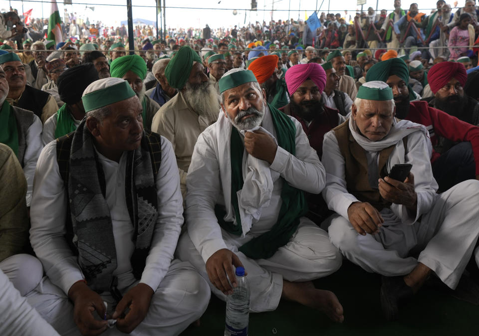 Farmer leader Rakesh Tikait , centre, sits with others during a rally at Ghazipur, on the outskirts of New Delhi, India, Friday, Nov. 26, 2021. Tens of thousands of farmers rallied on Friday marking one year of their movement that forced Prime Minister Narendra Modi to withdraw three agriculture laws that feared would drastically reduce their incomes and leave them at the mercy of corporations. (AP Photo/Manish Swarup)