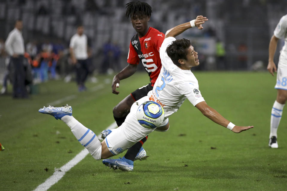 Marseille's Hiroki Sakai falls to the ground while battling for the ball with Rennes' Eduardo Camavinga during the French League One soccer match between Marseille and Rennes at the Velodrome stadium in Marseille, southern France, Sunday, Sept. 29, 2019. (AP Photo/Daniel Cole)