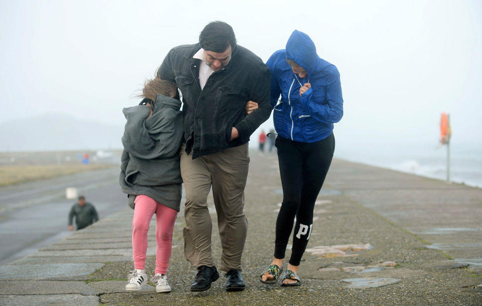 <p>A family walks along a seawall during storm Ophelia on East Pier in Howth, Dublin, Ireland, as the remnants of Hurricane Ophelia batter Ireland and the United Kingdom with gusts of up to 80mph (129kph), Monday Oct. 16, 2017. (Photo: Caroline Quinn/PA via AP) </p>