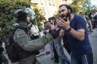 Israeli riot police tries to block a Jewish right-wing man as clashes erupted between Arabs, police and Jews, in the mixed town of Lod, central Israel, Wednesday, May 12, 2021. As rockets from Gaza streaked overhead, Arabs and Jews fought each other on the streets below. Rioters torched vehicles, a restaurant and a synagogue in one of the worst spasms of communal violence that Israel has seen in years. (AP Photo/Heidi Levine)