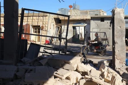 A man rides a motorcycle near a damaged site after an airstrike on rebel-held Urum al-Kubra town in Aleppo province, Syria November 2, 2016. REUTERS/Ammar Abdullah