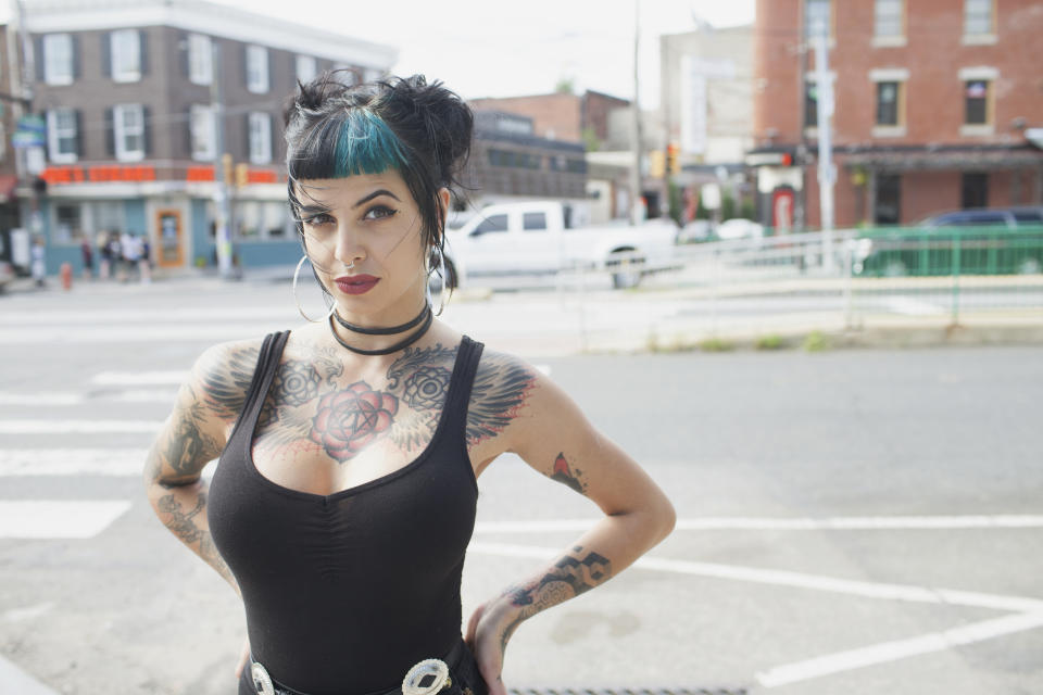 A portrait of a young woman tattoos and black and blue hair.