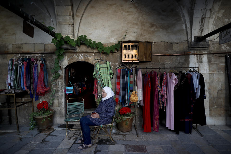 A Syrian shopkeeper waits for customers outside her shop in the Takiyya complex, an ancient construction with landscaped courtyards built on the banks of the Barada River in Damascus, Syria, Wednesday, Oct. 3, 2018. President Bashar Assad told a little-known Kuwaiti newspaper on Wednesday that Syria has reached a "major understanding" with Arab states after years of hostility over the country's civil war. (AP Photo/Hassan Ammar)