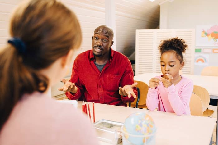 Man and girl engaged in a conversation with a woman across the table, in a room with educational posters