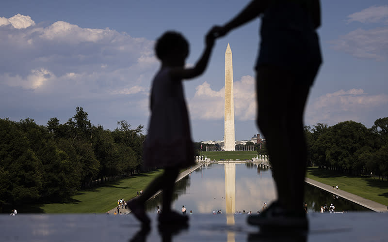 The Lincoln Memorial is seen in the distance, framed by the silhouettes in the foreground of an adult and child