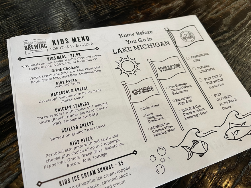 Last week, the owners at Three Blondes Brewing on Phoenix Street started printing new kids’ menus. On the menu, families will find a drawing that explains how the flag system works at the lakeshore.