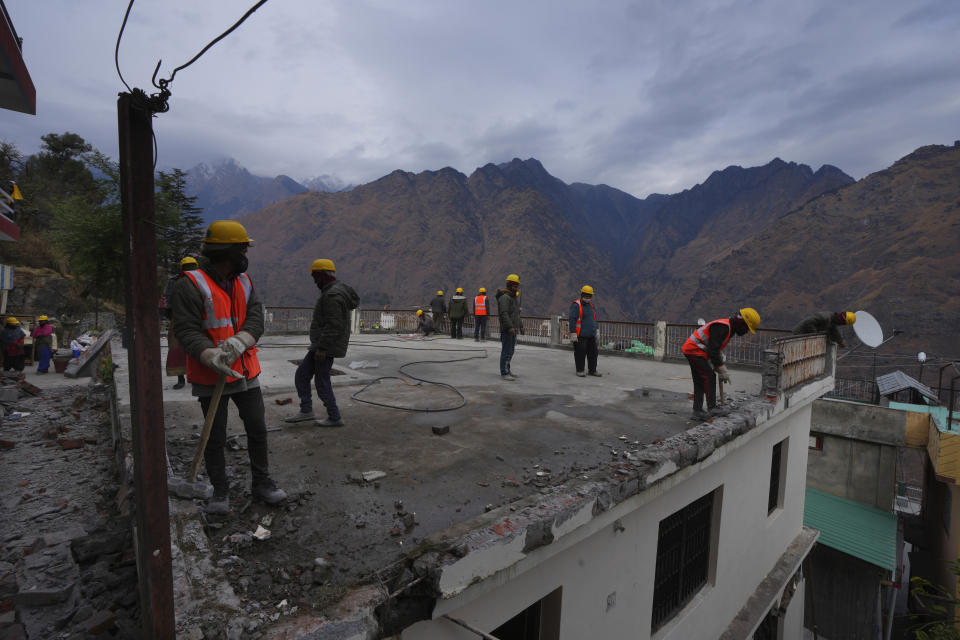 Laborers demolish a building which has developed cracks in Joshimath, in India's Himalayan mountain state of Uttarakhand, Jan. 19, 2023. Big, deep cracks had emerged in over 860 homes in Joshimath, where they snaked through floors, ceilings and walls, making them unlivable. Roads were split with crevices and multi-storied hotels slumped to one side. Authorities declared it a disaster zone and came in on bulldozers, razing down whole parts of a town that had become lopsided. (AP Photo/Rajesh Kumar Singh)