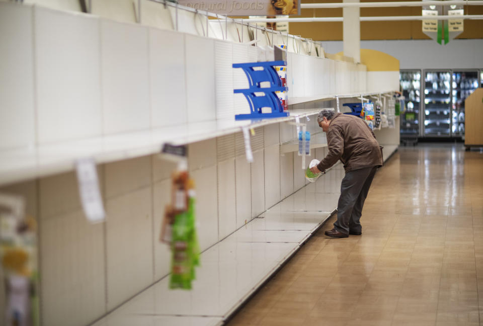 FILE - In this March 19, 2020 file photo, Wade Warner picks up a toilet paper roll at a Stop & Shop supermarket during hours open daily only for seniors in North Providence, R.I. Reaction to the coronavirus, change came to the United States during the third week of March in 2020. It did not come immediately, though it came quite quickly. There was no explosion, no invasion other than a microscopic one that nobody could see. (AP Photo/David Goldman)