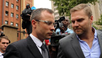 Oscar Pistorius, left, with unidentified relative leaves the high court in Pretoria, South Africa, Thursday, April 17, 2014. Pistorius is charged with murder for the shooting death of his girlfriend, Reeva Steenkamp, on Valentines Day in 2013. (AP Photo/Themba Hadebe)