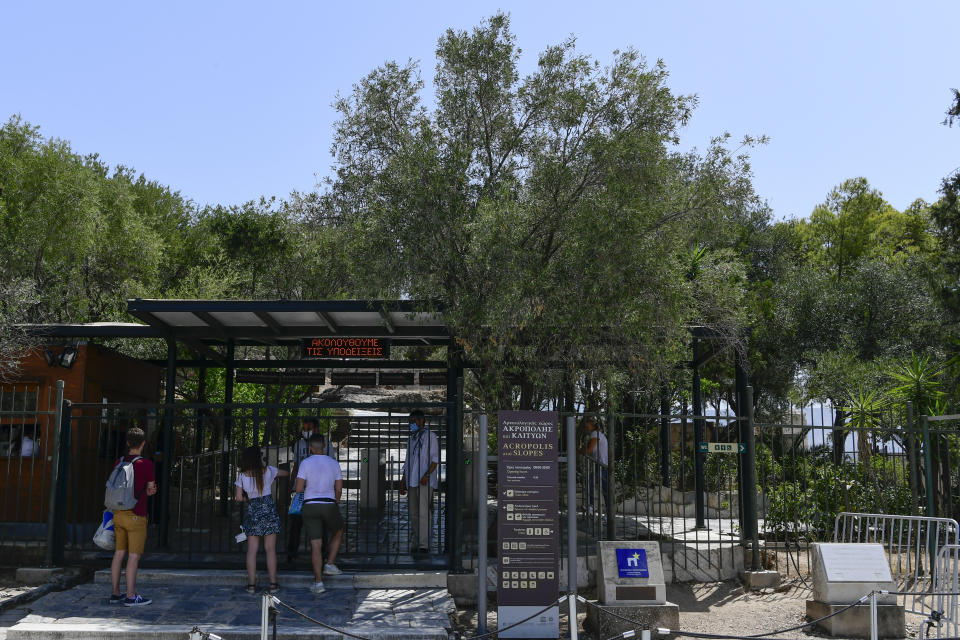 Tourists talk with staff of the ancient Acropolis, in Athens Greece, Tuesday, Aug. 3, 2021. Authorities in Greece have closed the Acropolis and other ancient sites during afternoon hours as a heatwave scorching the eastern Mediterranean continued to worsen. Temperatures reached 42 C (107.6 F) in parts of the Greek capital, as the extreme weather fueled deadly wildfires in Turkey and blazes across the region. (AP Photo/Michael Varaklas)