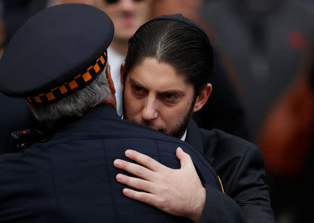 A family member embraces a police officer in front of Rodef Shalom Temple after funeral services for brothers Cecil and David Rosenthal, victims of the Tree of Life Synagogue shooting, in Pittsburgh, Pennsylvania, U.S., October 30, 2018. REUTERS/Cathal McNaughton