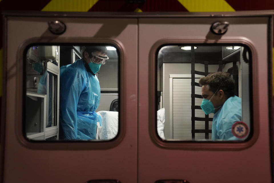 Emergency medical technician Thomas Hoang, left, of Emergency Ambulance Service, and paramedic Trenton Amaro prepare to unload a COVID-19 patient from an ambulance in Placentia, Calif., Friday, Jan. 8, 2021. EMTs and paramedics have always dealt with life and death — they make split-second decisions about patient care, which hospital to race to, the best and fastest way to save someone — and now they're just a breath away from becoming the patient themselves. (AP Photo/Jae C. Hong)