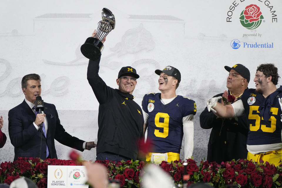 Michigan head coach Jim Harbaugh holds the winner's trophy next to quarterback J.J. McCarthy (9) and defensive lineman Mason Graham (55) after a win over Alabama in the Rose Bowl CFP NCAA semifinal college football game Monday, Jan. 1, 2024, in Pasadena, Calif. (AP Photo/Mark J. Terrill)