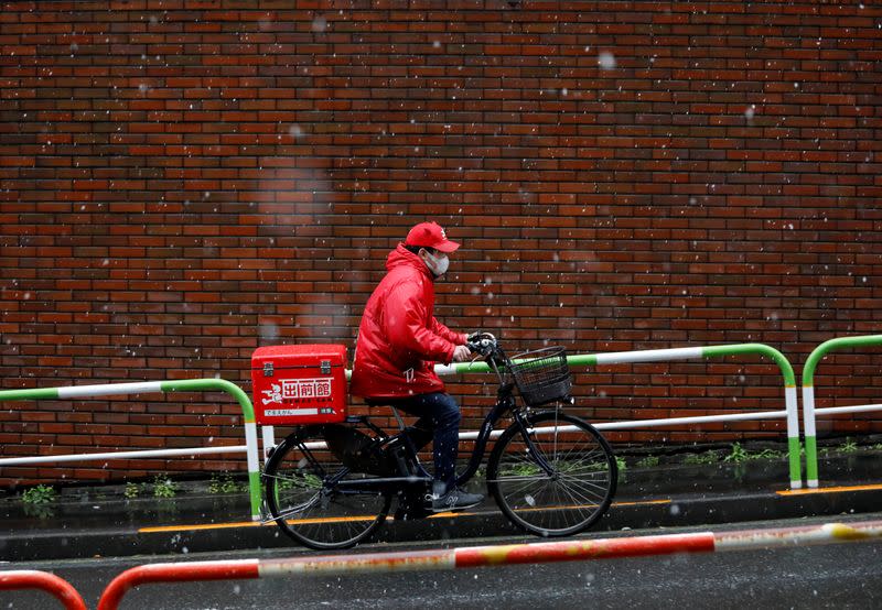 A food delivery service man rides on a street during snow fall in Tokyo