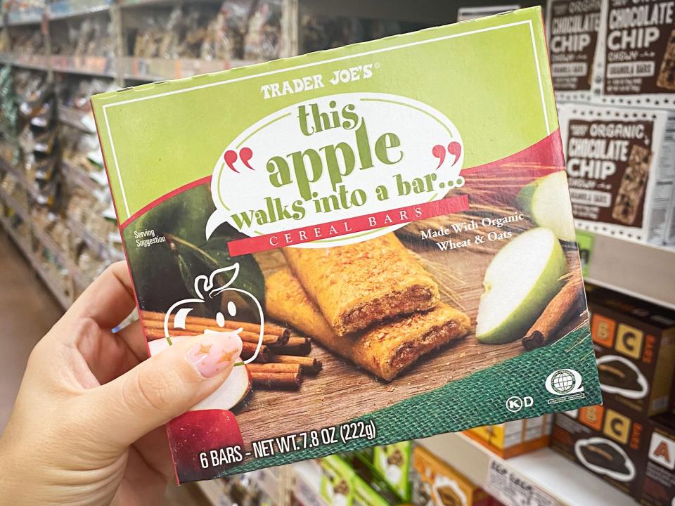 hand holding box of apple cereal bars in an aisle at trader joes