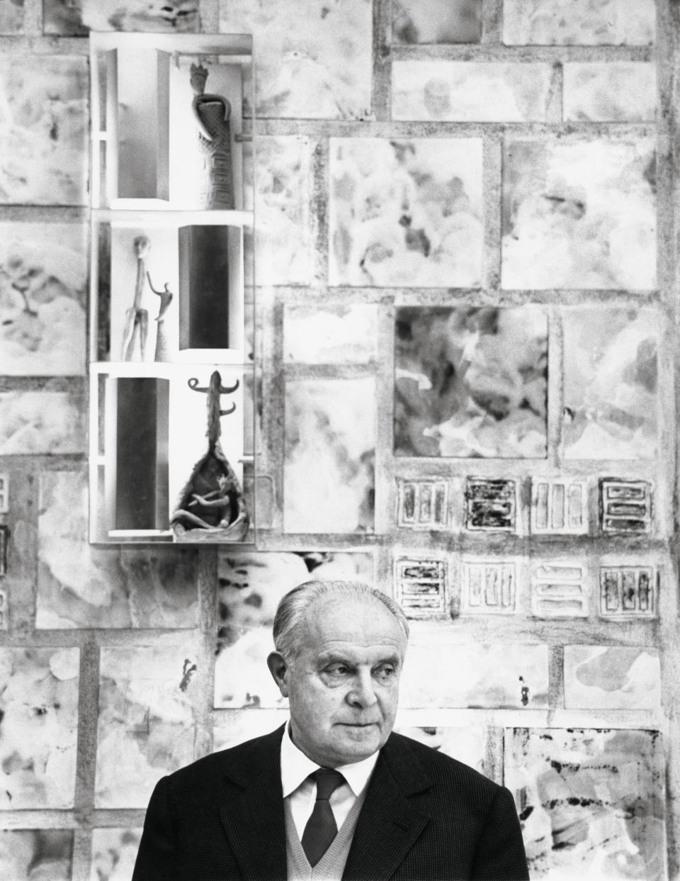 Gio Ponti in 1959 at the New York Alitalia office, with custom Fausto Melotti ceramic wall design, which includes three of the artist’s figurative sculptures placed inside Ponti’s illuminated brass sconce, a Quadro Luminoso, for Arredoluce, 1957.