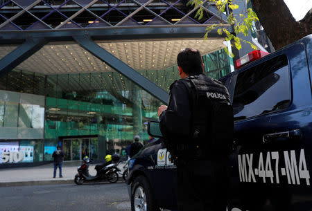 A police officer stands guard outside the tower after people were evacuated from the Mexican headquarters of Spain's BBVA due to what the bank said were two anonymous emails threatening violent acts against its corporate offices, in Mexico City, Mexico March 13, 2019. REUTERS/Henry Romero