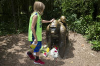 <p>A child touches the head of a gorilla statue where flowers have been placed outside the Gorilla World exhibit at the Cincinnati Zoo & Botanical Garden, Sunday, May 29, 2016, in Cincinnati. On Saturday, a special zoo response team shot and killed Harambe, a 17-year-old gorilla that grabbed and dragged a 4-year-old boy who fell into the gorilla exhibit moat. Authorities said the boy is expected to recover. He was taken to Cincinnati Children’s Hospital Medical Center. <em>(AP Photo/John Minchillo)</em> </p>