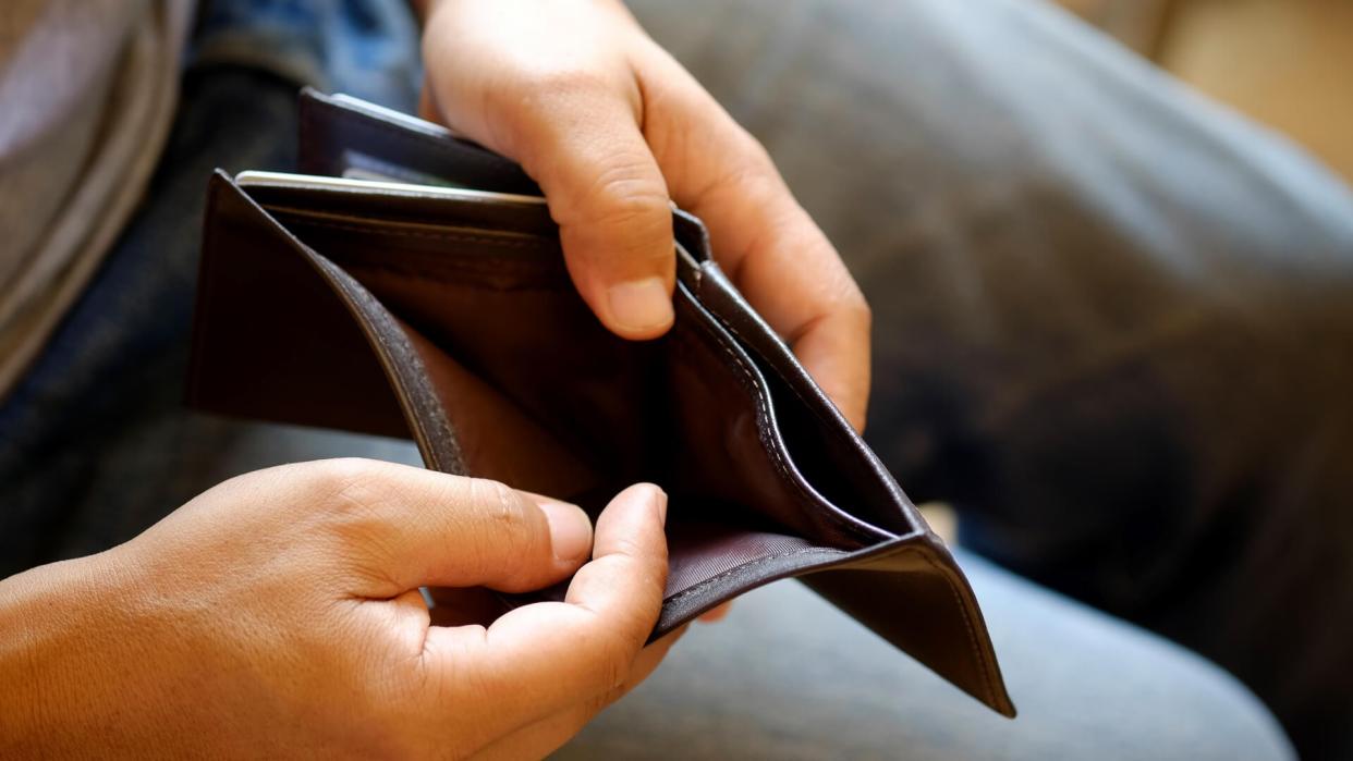 Man looking at his empty leather wallet in office.