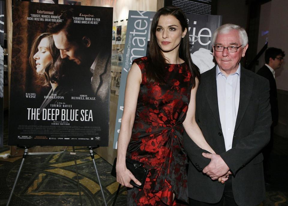 A woman in a red and black dress attends a movie premiere with her director.