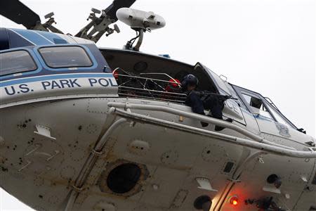 A law enforcement officer with a rifle sits in a helicopter above the scene of a shooting at the Washington Navy Yard in Washington, September 16, 2013. REUTERS/Jonathan Ernst