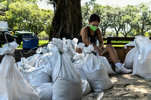 Una mujer recoge sacos de arena para proteger su vivienda en Palmetto Bay, cerca de Miami, cuando Florida se prepara para recibir el huracán Isaías (AFP | CHANDAN KHANNA)