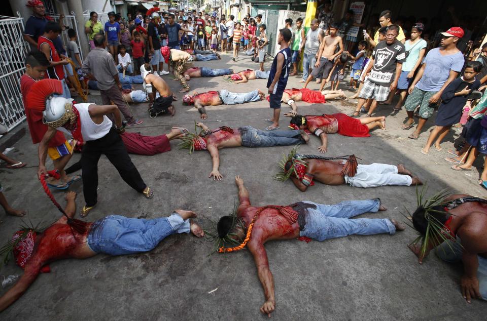 Flagellants lie prostrate on the ground as the pray outside a chapel during a Maundy Thursday ritual by penitents to atone for sins in Angeles