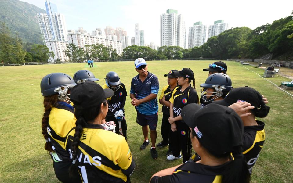 The SCC Divas cricket team get a team talk from coach Sher Lama (C) ahead of their game against the Hong Kong Cricket Club Cavaliers - PETER PARKS /AFP