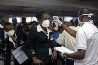 FILE - In this Wednesday, March 4, 2020 file photo, a Nigerian port health official, right, uses a thermometer to screen Ethiopian Airline cabin crews for the coronavirus, upon arrival at the Murtala Muhammed International Airport in Lagos, Nigeria. Questions are swirling in Africa and elsewhere over the financial wisdom of sustaining prestige carriers that have a tiny share of an aviation market that sees no recovery in sight as sub-Saharan Africa faces its first recession in a quarter-century amid coronavirus-related travel restrictions. (AP Photo/Sunday Alamba, File)