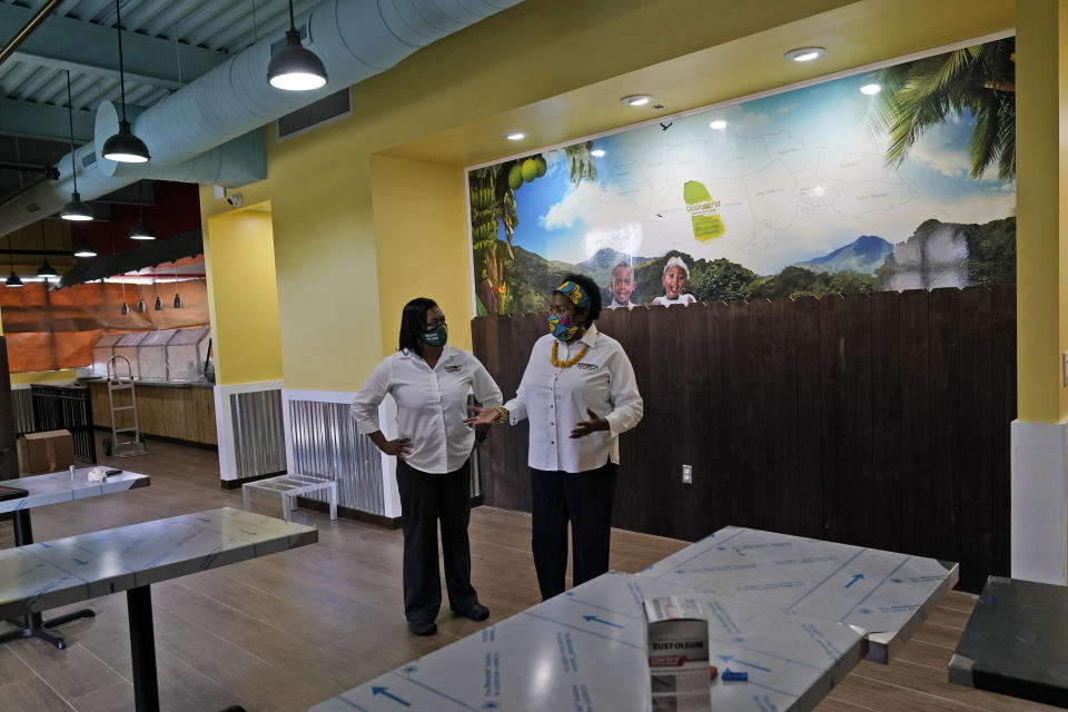 In this Aug. 26, 2020, photo Sophia Bramwell, left, and Antoinette Henry, right, talk at the soon to be opened Dutch Pot Jamaican Restaurant in Miami Gardens, Fla. Voters in the Democratic stronghold of Broward County are eager to defeat Trump, but say they are even more energized to turn out in support of California Sen. Kamala Harris, Biden’s running mate whose father is Jamaican. “The fact she has a lineage means you are going to see a lot of Jamaicans voting even if they were not doing so before,” said Henry, “Part of Jamaica will be in the White House.” (AP Photo/Lynne Sladky)