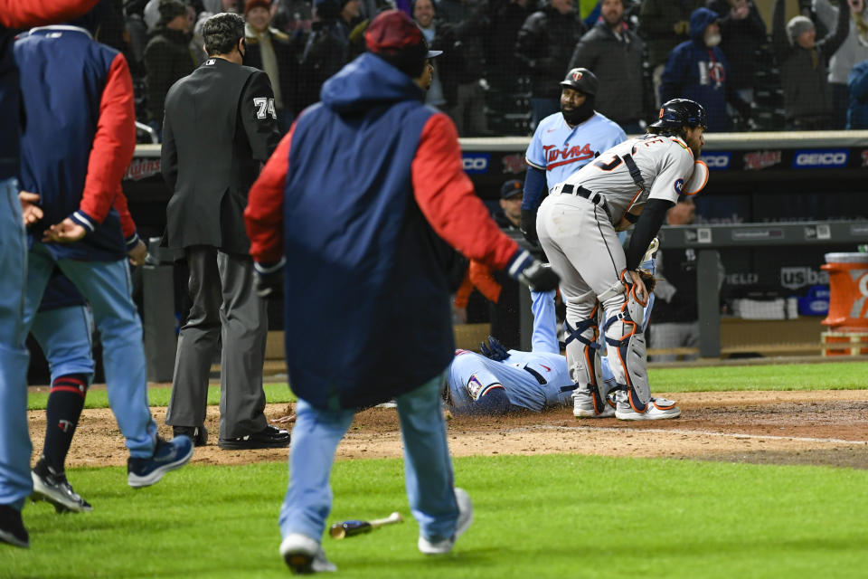 Detroit Tigers catcher Eric Haase, right, watches Minnesota Twins' Trevor Larnach heading to home plate as Twins' Gio Urshela slides across home plate and Twins players run onto the field after Haase made a throwing error to third during the ninth inning of a baseball game Tuesday, April 26, 2022, in Minneapolis. The Twins won 5-4. (AP Photo/Craig Lassig)