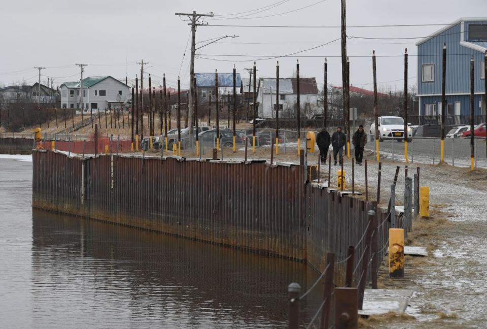 A wall shoring up a riverbank in a rural town.