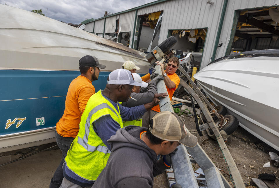 Standing between overturned boats, volunteers and staff of Scotty's Performance Boat & Marine attempt to salvage boats that fell off their respective trailers and were then pushed into a pile by strong winds during a tornado that hit Slidell, La., the day before. Parts of Slidell started picking up the pieces and cleaning up on Thursday, April 11, 2024. (Chris Granger/The Times-Picayune/The New Orleans Advocate via AP)