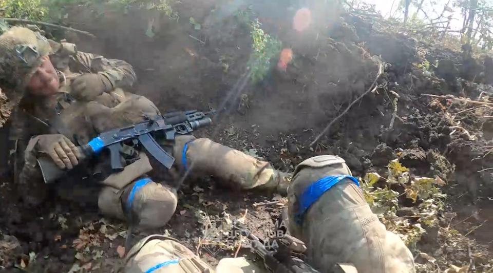 Ukrainian soldiers take cover in a wooded area amid gunfire, in this screen grab obtained from a social media video released on July 28 (UKRAINIAN ARMED FORCES)