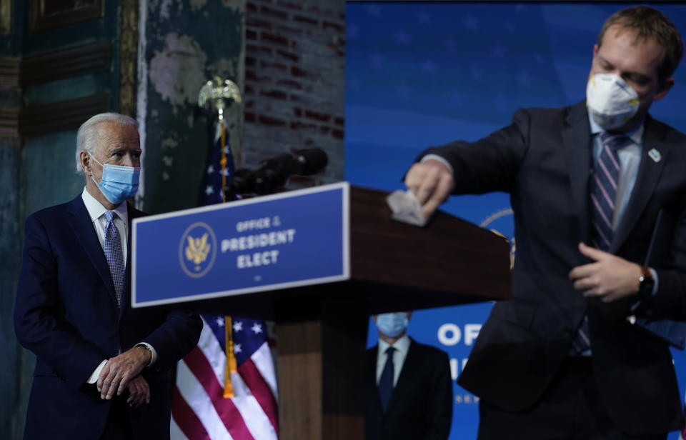 President-elect Joe Biden stands left as the podium is cleaned as he introduces his nominees and appointees to key national security and foreign policy posts at The Queen theater, Tuesday, Nov. 24, 2020, in Wilmington, Del. (AP Photo/Carolyn Kaster)