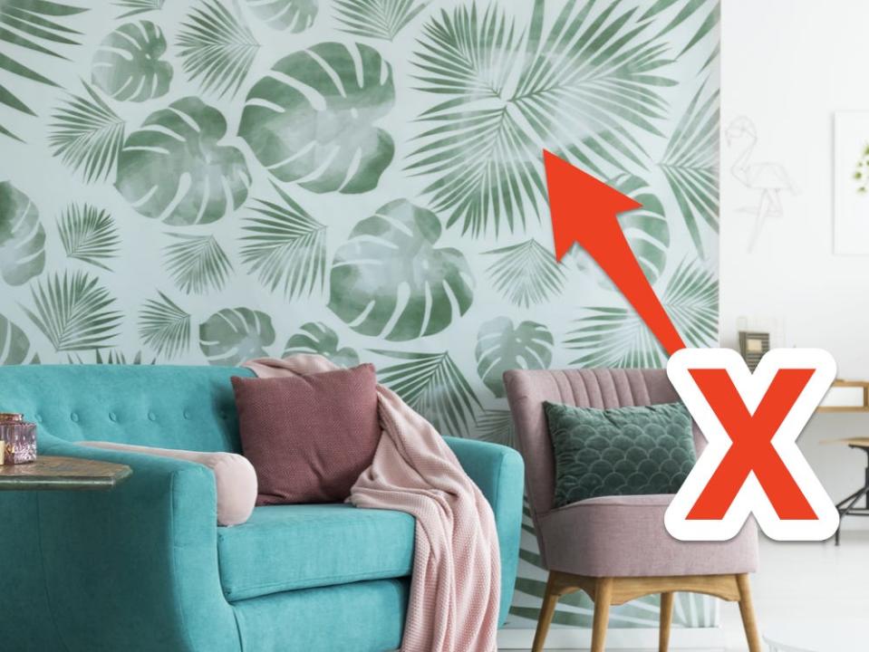 Living room with blue couch and palm-leaf wallpaper with red arrow and X pointing to wallpaper