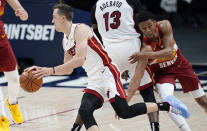 Miami Heat guard Duncan Robinson, left, drives past Denver Nuggets guard PJ Dozier during the first half of an NBA basketball game Wednesday, April 14, 2021, in Denver. (AP Photo/David Zalubowski)