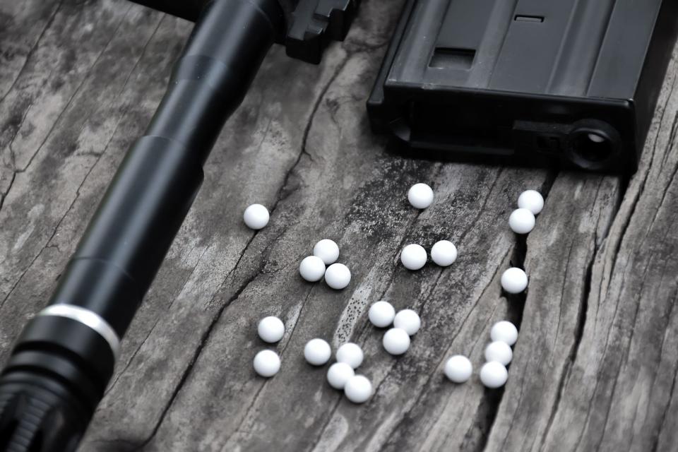 A closeup look at an airsoft gun and its corresponding ammunition.