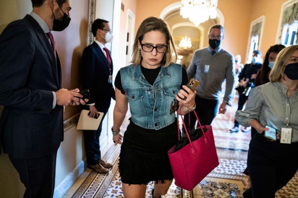 Kyrsten Sinema wears a denim vest over a black fringed dress at the Capitol