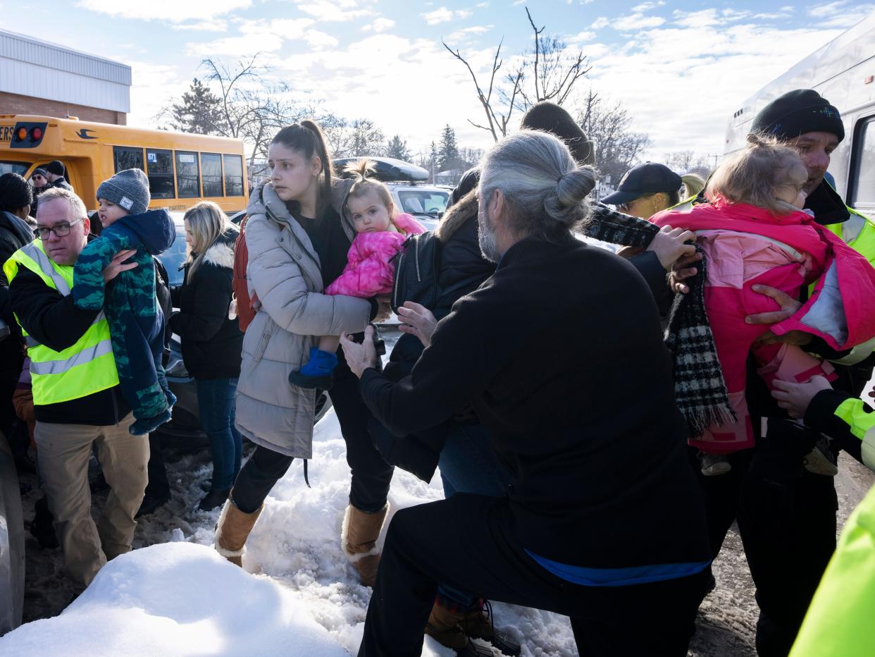 Parents and their children are loaded onto a warming bus as they wait for news after a bus crashed into a daycare centre in Laval, Quebec, on Wednesday, Feb. 8, 2023 (AP)