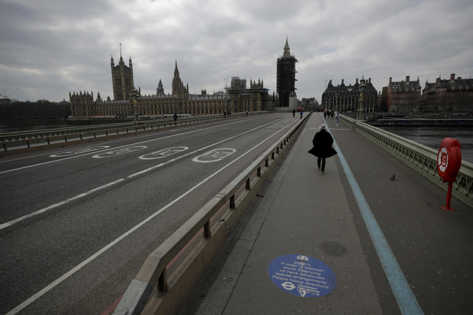 FILE - In this Tuesday, March 23, 2021 file photo, people cros over a quiet Westminster Bridge, backdropped by the scaffolded Houses of Parliament and the Elizabeth Tower, known as Big Ben, in London, during England's third coronavirus lockdown. Thanks to an efficient vaccine roll out program and high uptake rates, Britain is finally saying goodbye to months of tough lockdown restrictions. From Monday May 17, 2021, all restaurants and bars can fully reopen, as can hotels, cinemas, theatres and museums, and for the first time since March 2020, Britons can hug friends and family and meet up inside other people’s houses. (AP Photo/Matt Dunham, File)