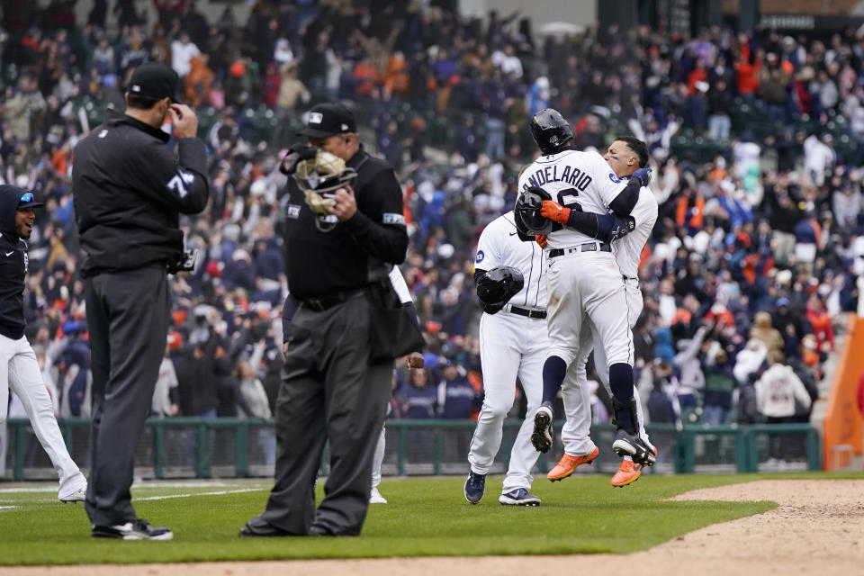 Detroit Tigers greet Javier Baez, right, after hitting a walk-off single during the ninth inning of a baseball game against the Chicago White Sox, Friday, April 8, 2022, in Detroit. The umpires were ruling on the play which was initially called an out. (AP Photo/Carlos Osorio)