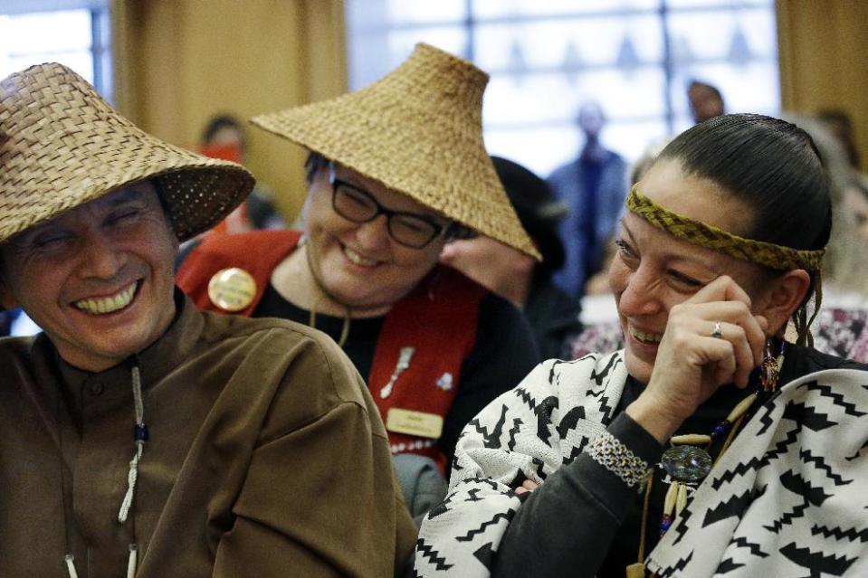 Olivia One Feather, right, of the Standing Rock Sioux tribe, Jessica Dominy, center, of the Muckleshoot tribe, and Paul Cheoketen, of the Wagner Saanich First Nations, smile after the Seattle City Council voted to divest from Wells Fargo, Tuesday, Feb. 7, 2017, in Seattle. The City Council voted to divest $3 billion in city funds from Wells Fargo over its funding of the Dakota Access Pipeline. (AP Photo/Elaine Thompson)