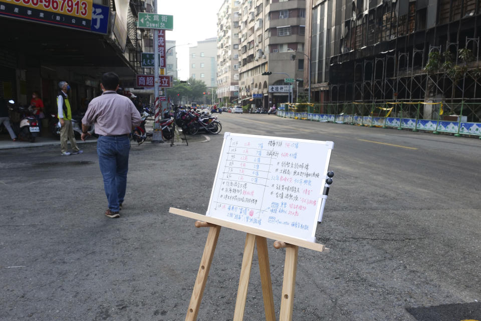 A whiteboard details the death and injury numbers near a burnt building in Kaohsiung in southern Taiwan on Friday, Oct. 15, 2021. Dozens were killed and dozens more injured after a fire broke out early Thursday in a decades-old mixed commercial and residential building in the Taiwanese port city of Kaohsiung, officials said. (AP Photo/Huizhong Wu)